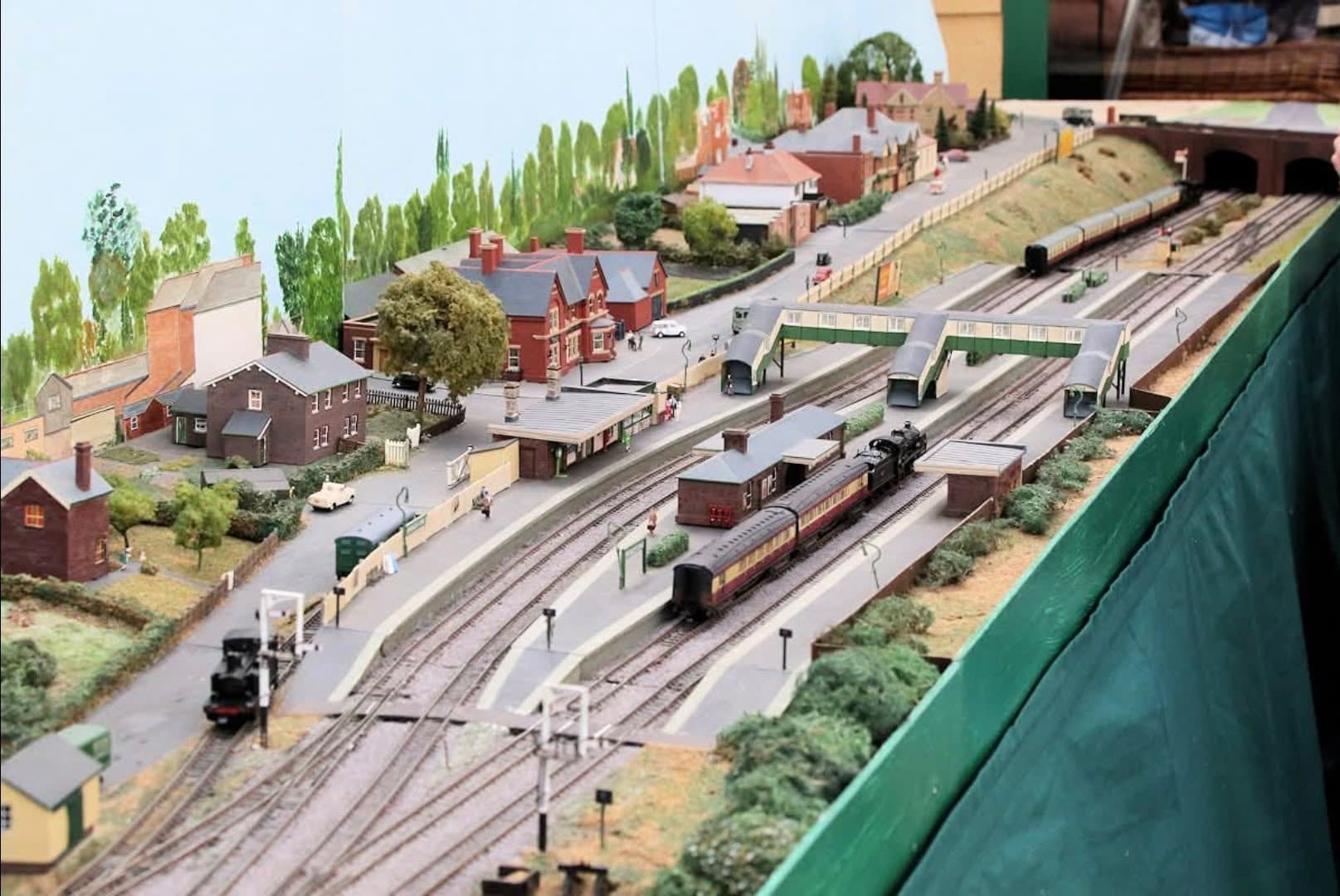 Broadstone station from above: a tank engine with maroon coaches at the platform, under the covered footbridge, with the Railway Hotel and the tunnels beyond